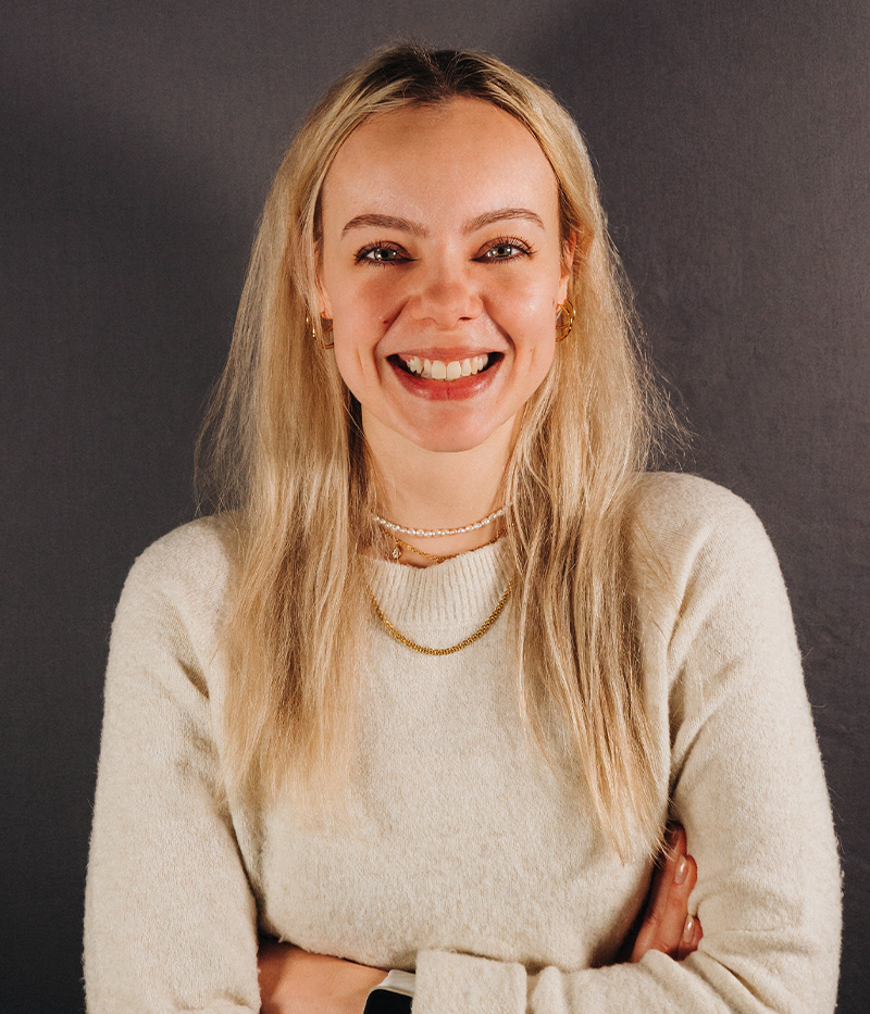 Auf dem Bild sieht man Julia Marie Stebele, eine blonde sympathisch Frau die lächelt und ein beiges Oberteil trägt